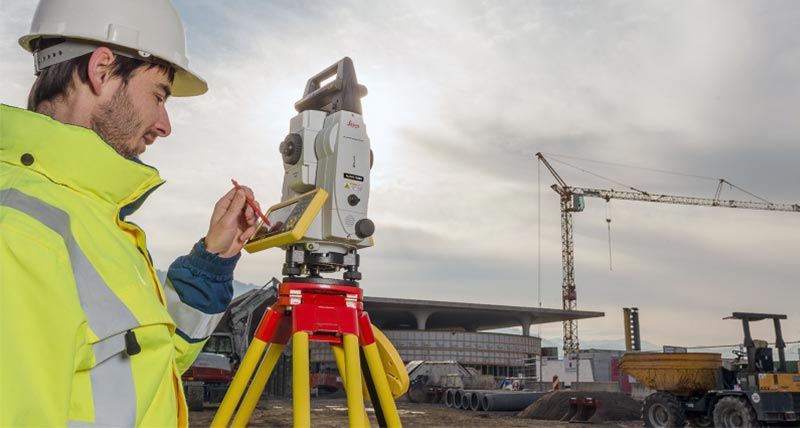 Un ouvrier utilise une station totale robotisée Leica iCON iCR80 sur un chantier extérieur.